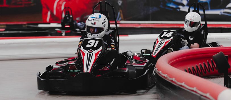 K1 Speed racers competing wheel to wheel through a corner on an indoor electric karting track